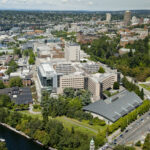 Aerial photo of the UW Seattle Campus, featuring intersecting streets, buildings, bridges, and landscape architecture of campus by Drumheller Fountain