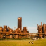 Large metal structures in a field of grass with people sitting and talking.