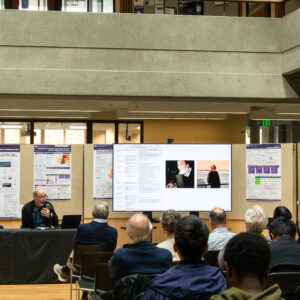 Crowd listening to speaker giving presentation on screen